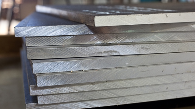 Grande lote de peças metálicas empilhadas aguardando processamento na fábrica